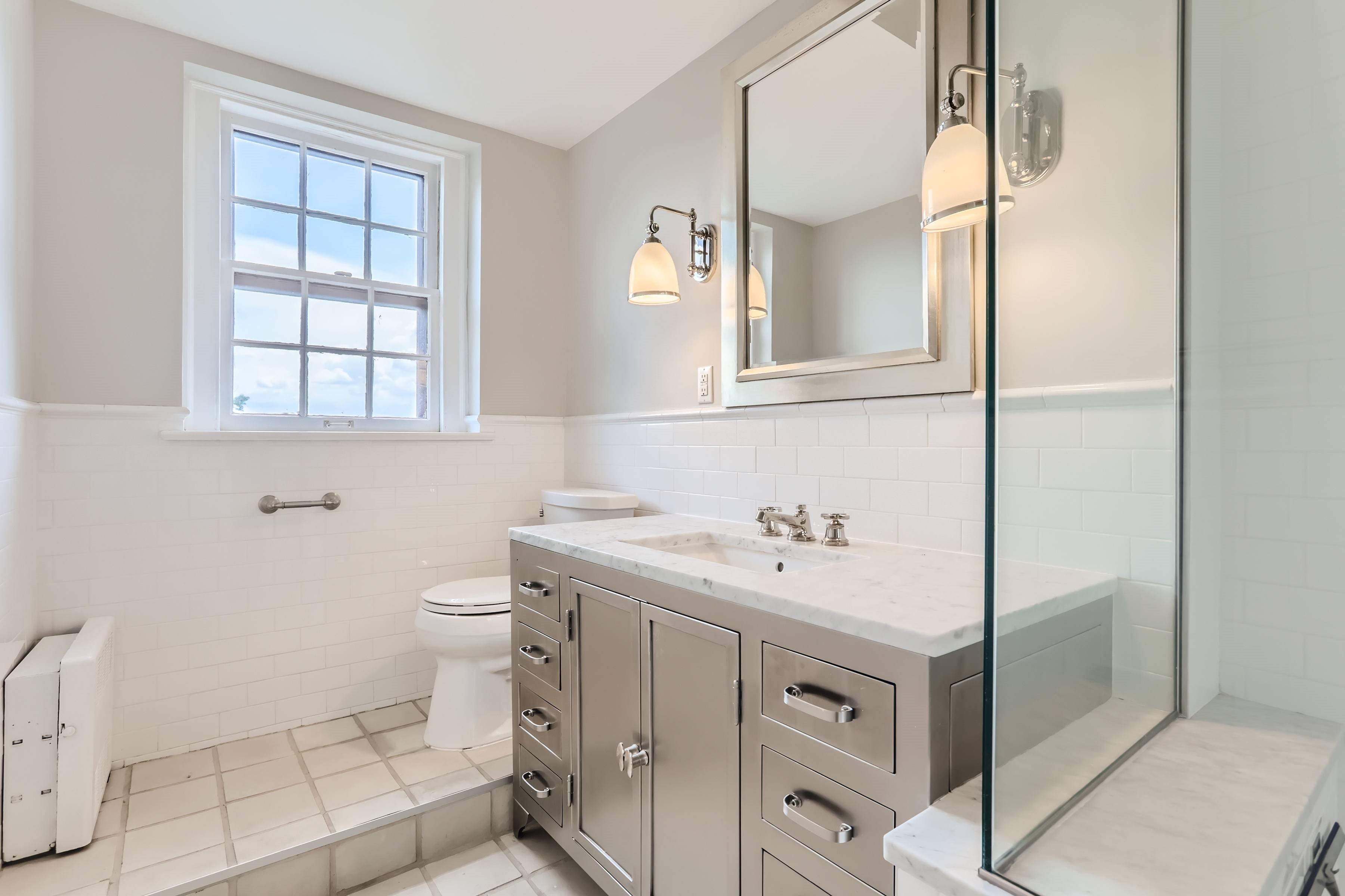 A bathroom with a toilet, sink, and mirror.